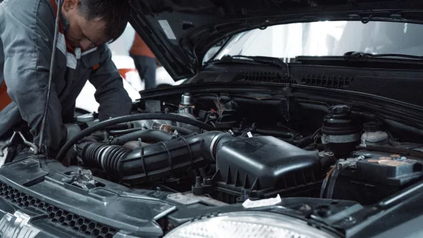 Mécanicien inspectant le compartiment moteur d'une voiture dans un atelier